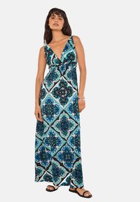 Maxi-jurk met een diepe V-hals, featuring een blauw, zwart, en teal geometrisch patroon, zachte stof, en een losse pasvorm.