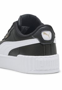 Schwarzer Ledersneaker mit weißen Akzenten, strukturiertem Profil, runder Form und markenspezifischen Details, darunter ein kleines Puma-Logo in Gold und Weiß.