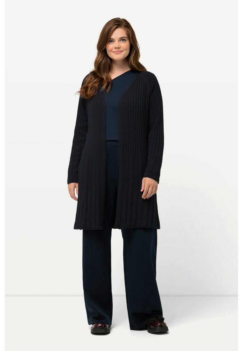 Lång, mörk marinblå kashmirtröja med ribbad textur, öppen fram, och långa ärmar, bärs över en matchande topp och löst sittande byxor.