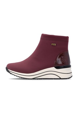 Bordeauxfarbene Stiefelette mit weißer Plateausohle, strukturierter schwarzer Außensohle, glänzendem Absatzdetail und kleinem goldfarbenem Logo-Emblem an der Seite.