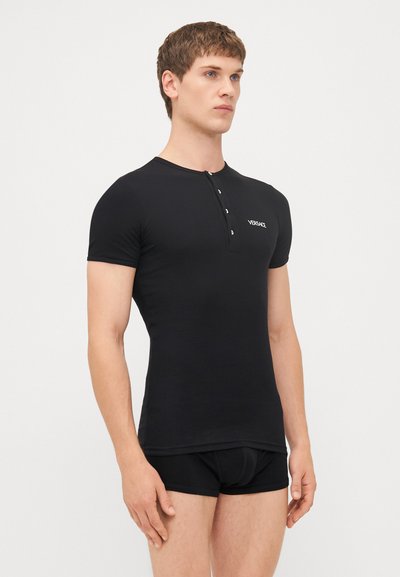 Schwarzes kurzärmliges Henley-Shirt aus glattem Stoff mit runder Halslinie, einer Drei-Knopf-Leiste und gesticktem Logo auf der linken Brust.