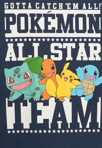 Navy blue T-shirt features cartoon Pokémon characters: Bulbasaur (green), Charmander (orange), Pikachu (yellow), and Squirtle (blue) with bold text.