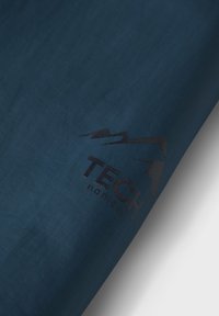 Sección de tela azul oscuro con un logo negro de "TECH nordic" que presenta picos montañosos estilizados sobre un fondo claro.