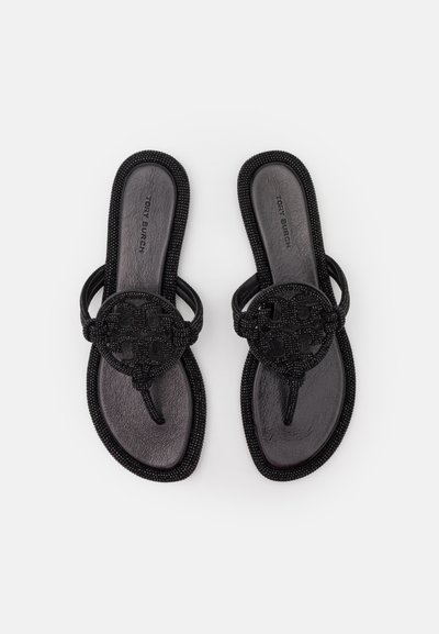 Sandales plates noires avec un design perlée, présentant un accent logo rond et une semelle en cuir lisse. Les brides sont délicates et arrondies.