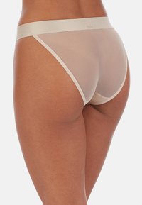 Beżowy przezroczysty string wykonany z lekkiego, elastycznego materiału. Posiada szeroki elastyczny pas w talii oraz minimalistyczny design zapewniający minimalne zakrycie.