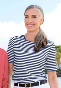 Navy en wit gestreepte t-shirt met korte mouwen en een ronde hals, gecombineerd met een zwarte riem, gedragen met lichtgekleurde broeken.