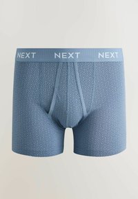 Boxeri bărbătești bleu deschis cu un model geometric hexagonal și o talie inscripționată cu "NEXT" cu litere mari albe.