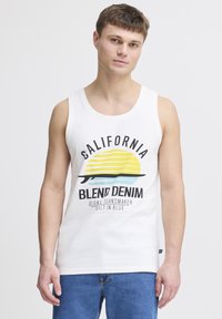 Tricou fără mâneci din bumbac alb, prezentând o grafică colorată cu un soare și dungi, etichetat "California Blend Denim" cu text bold negru.