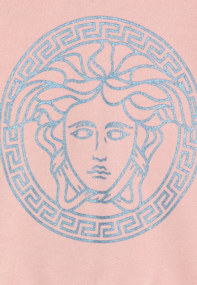 Rosa stof præsenterer et blåt Medusa-emblem med detaljeret hår og en geometrisk græsk nøglekant. Designet er centreret og fremtrædende.