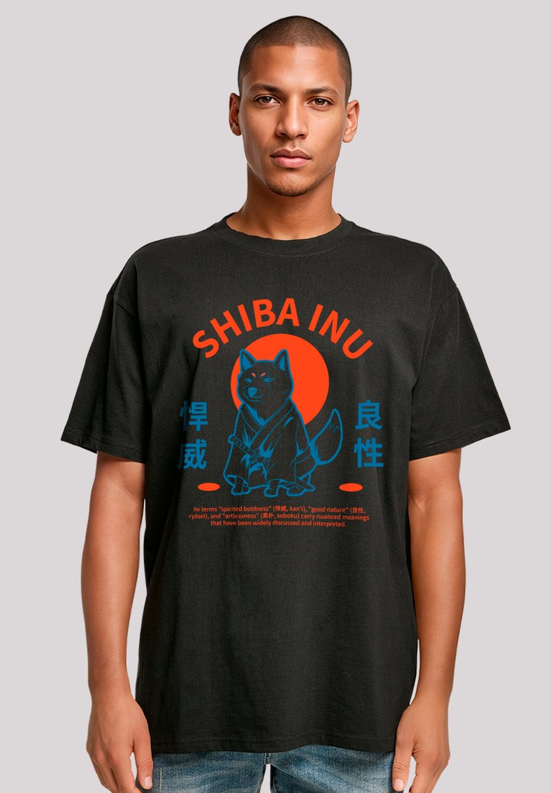 Schwarzes T-Shirt mit einem Grafikdesign eines Shiba Inu, rotem und blauen Text sowie einem kreisförmigen Hintergrund, der japanische Schriftzeichen darstellt.