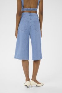Blå denim culottes med en avslappet passform, med høy midje og baklommer, paret med kremfargede hæl-sko.