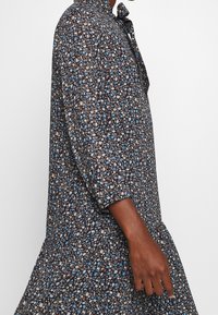 Navy floral dress with three-quarter sleeves, featuring multicolored flowers, a loose fit, and a tiered hemline. Made of soft fabric.