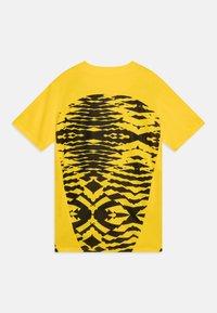 T-shirt giallo a maniche corte con un ampio motivo astratto nero sul retro, con una texture liscia e un design a vestibilità rilassata.