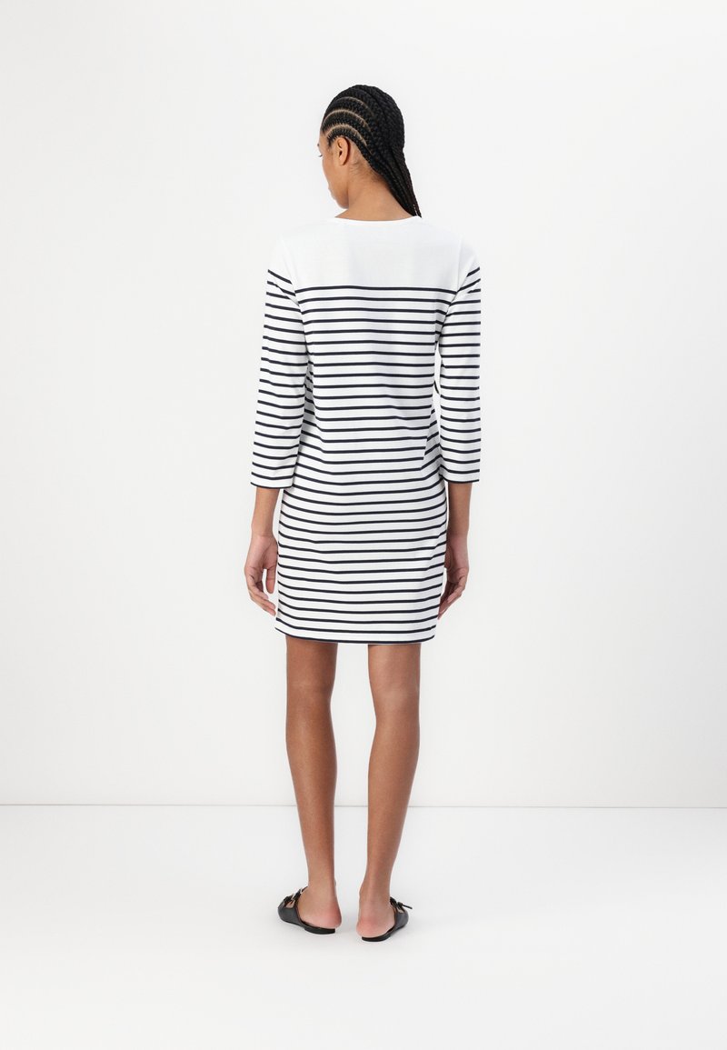 Pasiasta sukienka z rękawami do łokcia, w poziome czarne i białe pasy, wykonana z miękkiego materiału, długość do kolan i okrągły dekolt.
