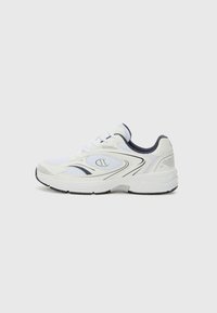 Zapatilla deportiva blanca con detalles de malla, acentos negros, suela acolchada y curvas suaves. Presenta un logo en el lateral y una suela de goma negra.