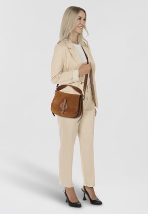 Bolso bandolera de ante marrón con detalles de cuero y una hebilla decorativa, con una cómoda correa para el hombro. Diseño simple y rectangular.