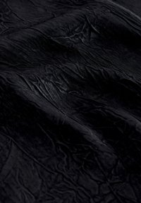 Crinkled black fabric with a smooth texture, exhibiting subtle sheen and varied patterns from folds and creases.