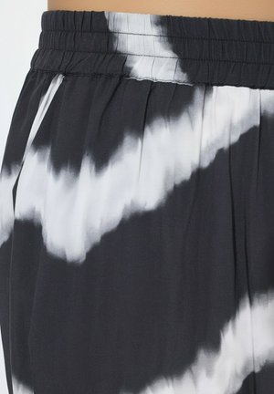 Zwart-witte tie-dye broek met elastische taille, geplooide stof en zichtbare zijzak aan de linkerkant.