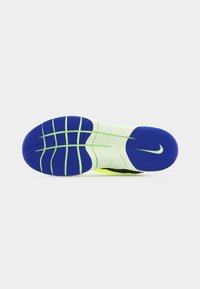 Semelle en caoutchouc d'une chaussure de sport avec des zones de grip texturées bleues et des rainures flexibles vert pâle, présentant un logo Nike swoosh sur la section du talon.