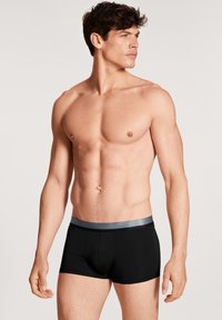 Zwarte boxer briefs met een zilveren elastische tailleband, met een textuur die glad is en een aansluitend ontwerp voor comfort en ondersteuning.