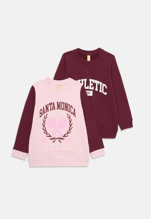Deux sweat-shirts à manches longues, un bordeaux avec l'inscription "ATHLETIC 97", un rose avec des manches bordeaux et le texte "SANTA MONICA Tennis Club" accompagné de raquettes croisées.