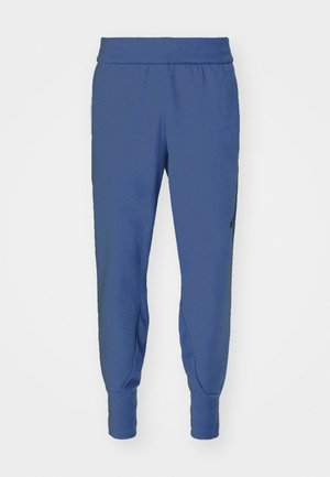 Pantaloni jogger blu realizzati in tessuto morbido, con vita elastica, caviglie affusolate e una tasca laterale. Tessura liscia.