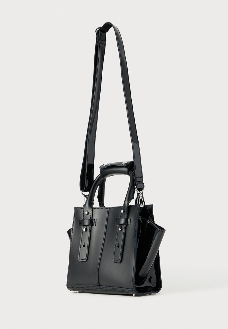 Sac à main noir en similicuir avec un design structuré, doté de deux poignées supérieures, d'une bandoulière amovible et d'accents en cuir verni brillant.