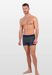 Blauwe gemusterde boxershorts van rekbaar materiaal, met een donkere tailleband en intricat draaiende patronen in lichte kleuren.