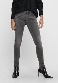 Šedé skinny džíny z denimu s vybledlým vzhledem a jemnými švy. Spárované s černými vysokými kotníkovými botami.