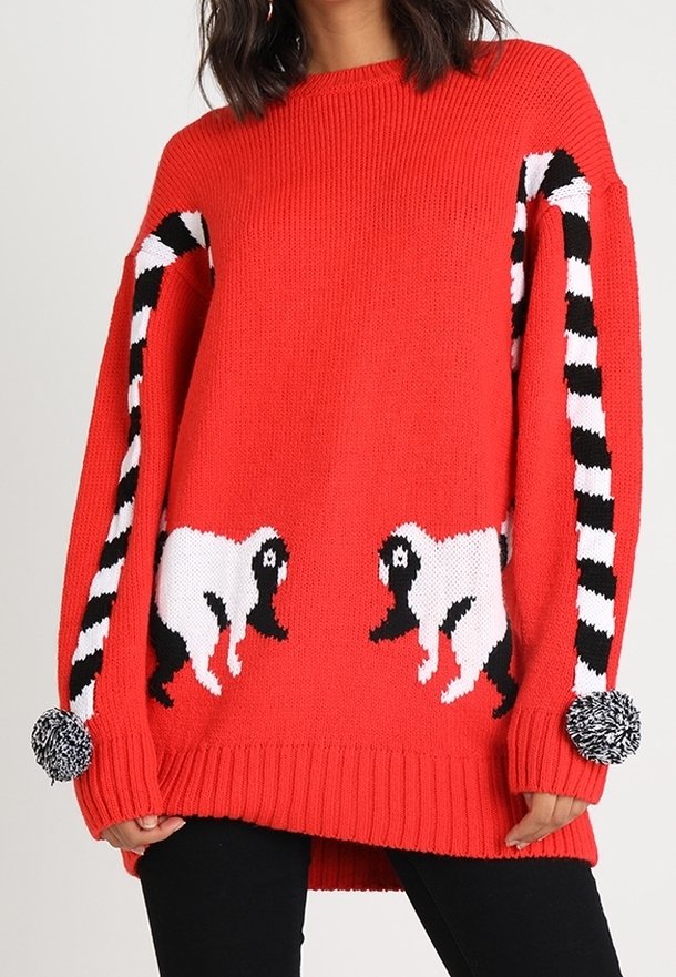 Maglione rosso lavorato a maglia con design di pecore bianche e nere sul davanti e maniche a righe bianche e nere, con dettagli in pom-pom sui polsini.