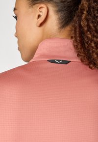 Langärmliges Hemd mit hohem Kragen aus weichem Korallstoff mit texturiertem Muster. Verfügt über ein schwarzes Logo-Tag auf der Rückseite.