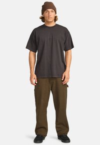 Mörkgrått bomulls t-shirt med korta ärmar, matchat med bruna cargobyxor med sidofickor och svarta sneakers. Brun stickad mössa.