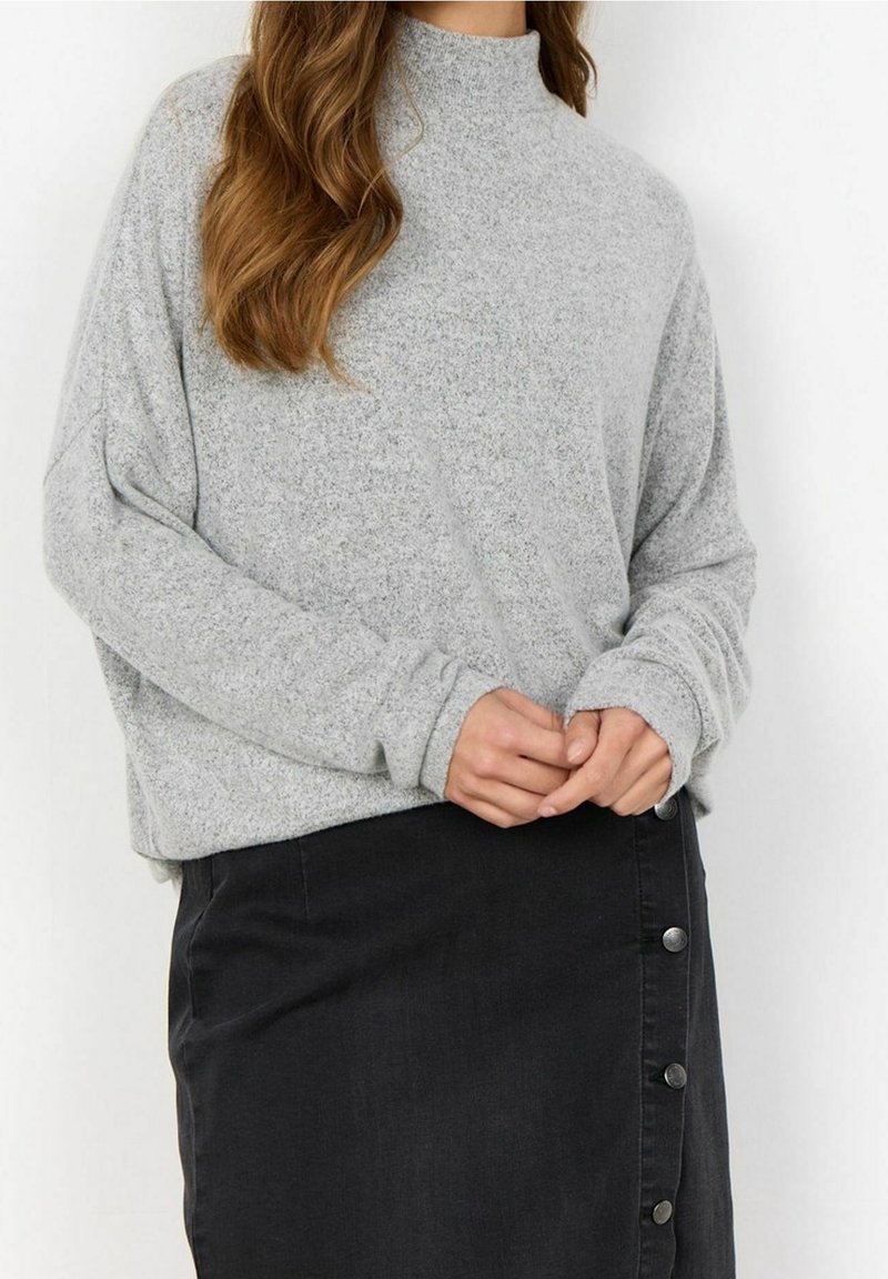 Lys grå, langærmet sweater med høj hals, der har en løs pasform og blød tekstur, parret med en sort denimnederdel med knapdetaljer.
