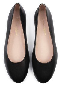 Bailarinas de cuero negro con puntera redondeada, laterales bajos y textura suave. El interior presenta una plantilla beige y un branding mínimo.