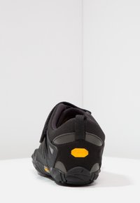 Czarne buty sportowe z materiałową cholewką i gumową podeszwą. Posiadają logo Vibram, pasek na rzep oraz teksturowany obcas zapewniający przyczepność.