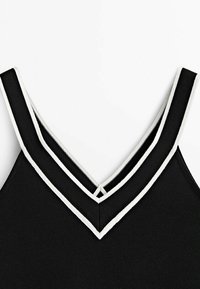 Top nero senza maniche con tessuto texturizzato e un bordo bianco a doppio strato in design a V, con spalline larghe e una finitura pulita.
