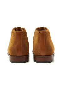 Brown suede ankle boots with a smooth leather accent on the heel. Finished with a wooden sole and perforated detailing on the back.