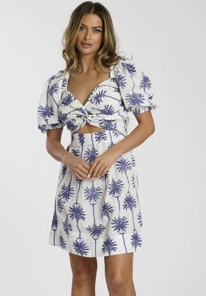 Witte jurk met paars palmboomprint, korte pofmouwen en een geknoopt voorpand. Halflang met een aansluitende taille en een uitlopende rok.