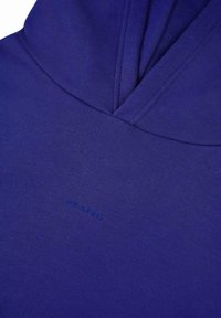 Violeta kapuce, izgatavota no mīksta auduma, ar priekšējo kangaru kabatu un smalku "OH APRIL" logotipu, ar kapuci ar auklu un teksturētu sajūtu.