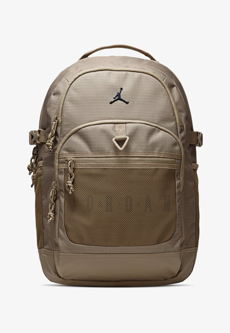 Beiger Rucksack mit vorderer Netztasche, Reißverschluss, verstellbaren Trägern und schwarzem Logo. Besitzt strukturierten Stoff und verstärkten Boden.