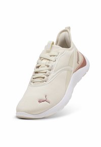Zapatilla deportiva de color crema claro con parte superior de malla, cierre con cordones, logotipo rosa y suela de goma. Forma contorneada con cuello acolchado para mayor comodidad.