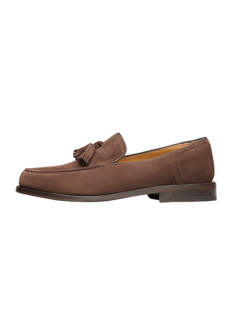 Mocassino in suede marrone con un accento a nappina, punta arrotondata e suola in legno, caratterizzato da una superficie liscia e linee pulite.