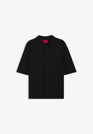 Mustaa, lyhythihaista ribbineulosta olevaa paitaa, jossa on nappikiinnitys edessä ja klassinen kaulus. Sisäinen merkintä on kirkkaanpunainen.