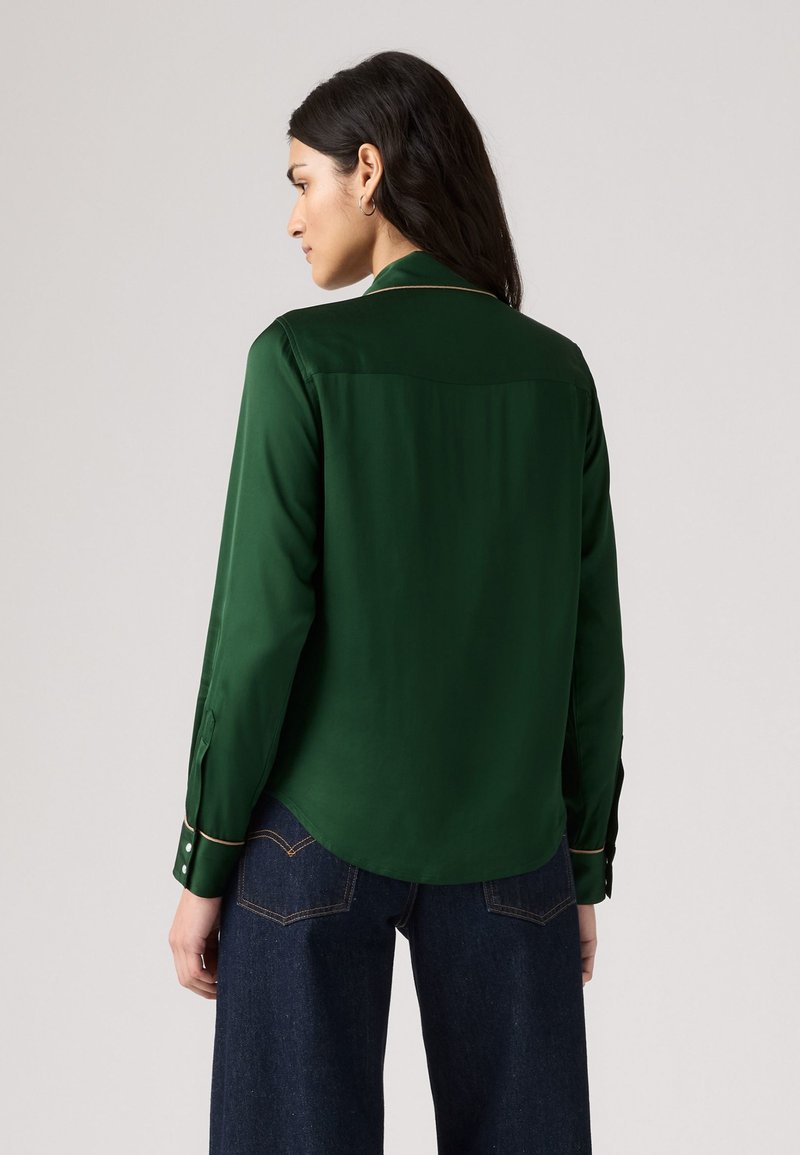 Green silk shirt with a collar, back yoke detail, and buttoned cuffs. Features contrasting gold accents and a curved hem.