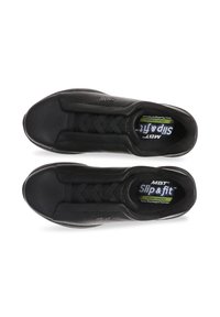 Scarpe slip-on nere in pelle texturizzata con punta arrotondata e lacci elastici incrociati. Presentano una soletta imbottita con il marchio "MBT Slip & Fit".