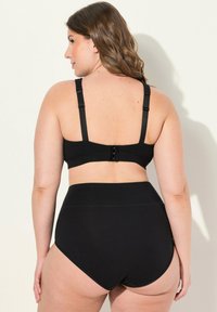Conjunto de sujetador negro y bragas de cintura alta con tirantes ajustables. Textura suave y diseño minimalista, con cierre de gancho y ojo.