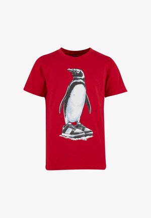 T-shirt rouge à manches courtes avec un graphique représentant un pingouin portant des baskets noires et blanches, debout sur la glace.