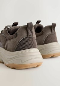 Gray suede and mesh sneakers with a thick cream sole, featuring a textured back and pull tabs for easy wear.