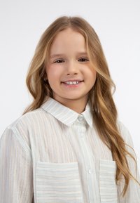 Hvid skjorte med lyseblå og metallisk guld lodrette striber, der har to forlommer og en klassisk krave.