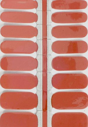 Set of rectangular nail polish strips in varying shades of coral pink, glossy finish, with a smooth texture and white adhesive backing.
